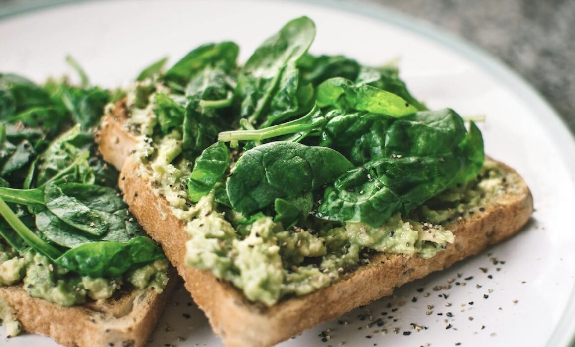 avocado and basil on toast on a white plate