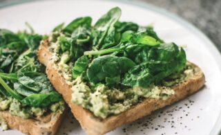 avocado and basil on toast on a white plate