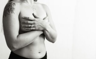 black and white photo of a shirtless woman holding her chest