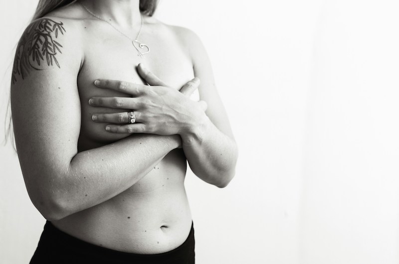 black and white photo of a shirtless woman holding her chest