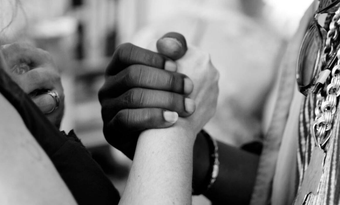 black and white photo of two people holding hands very close up on the hands