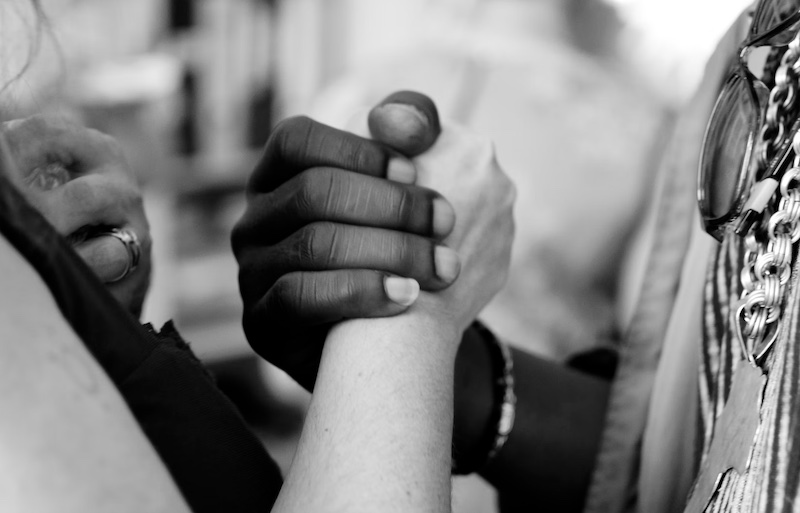 black and white photo of two people holding hands very close up on the hands