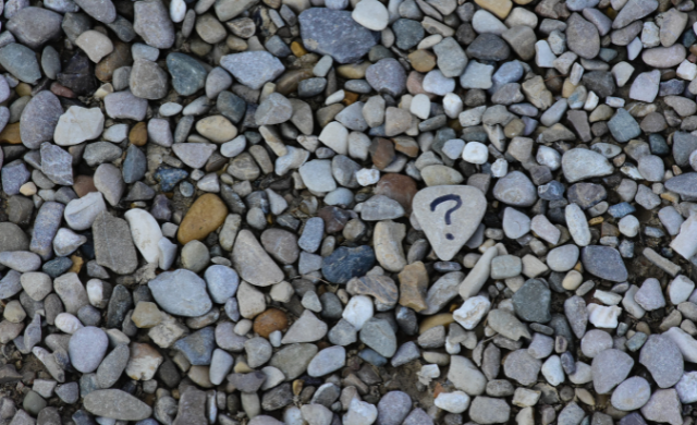 Some stones on a beach with a question mark on one of them