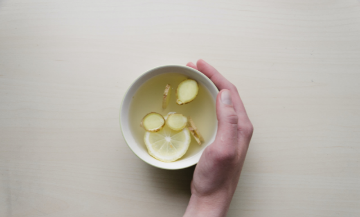 A hand holding a cup of lemon and ginger tea