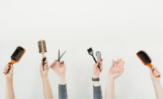 Hands holding hair brushes, combs and scissors