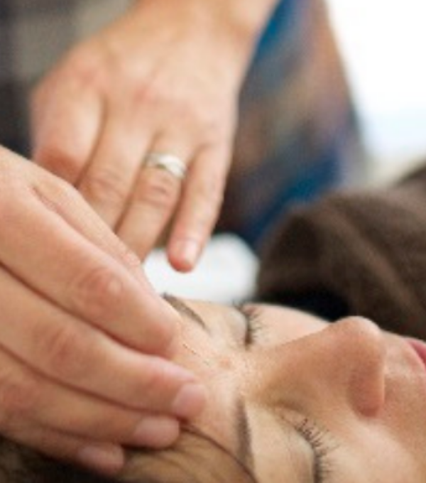 Close up of an acupuncturist's hands treating a patient, touching their forehead.