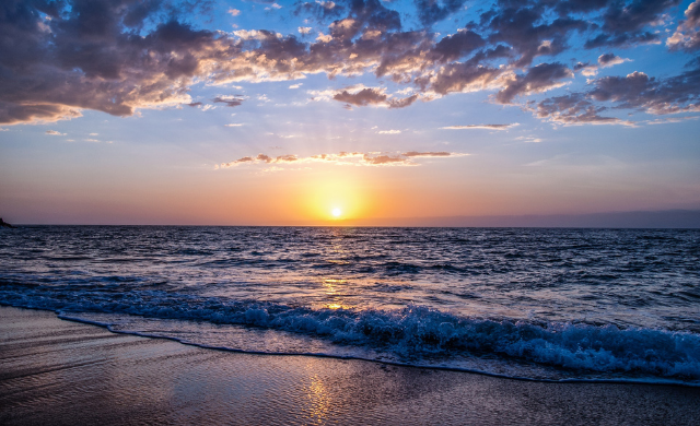 beach sunset, clouds in the dark blue sky, gentle waves on the sandy beach