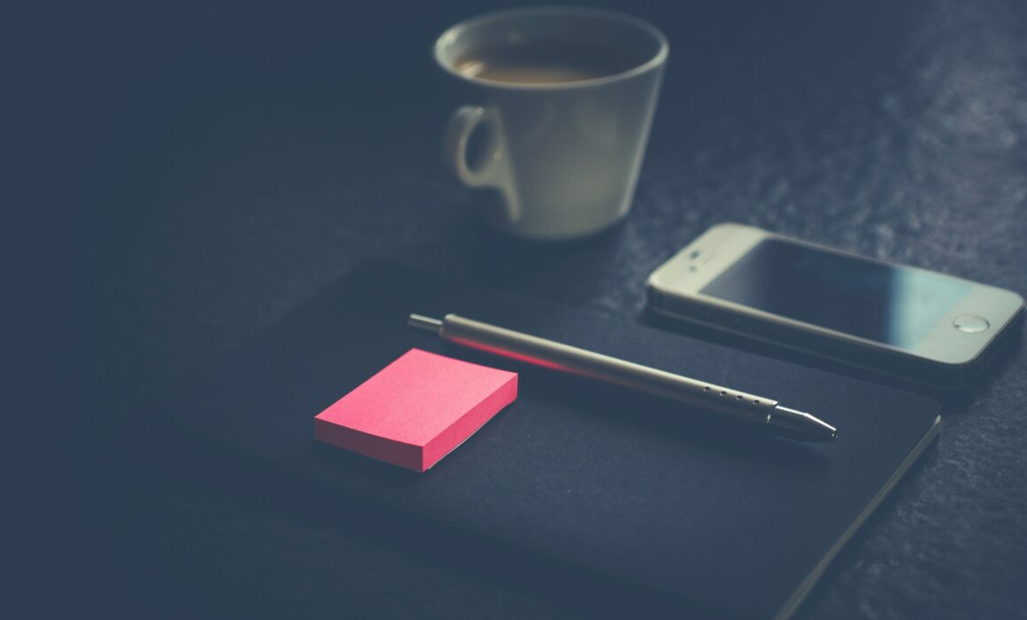 phone, pink post it notes, cup of tea