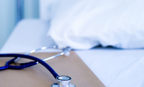 hospital bed and table with stethoscope.