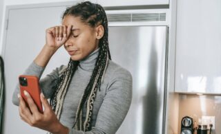 A woman looking sad as she holds up her phone