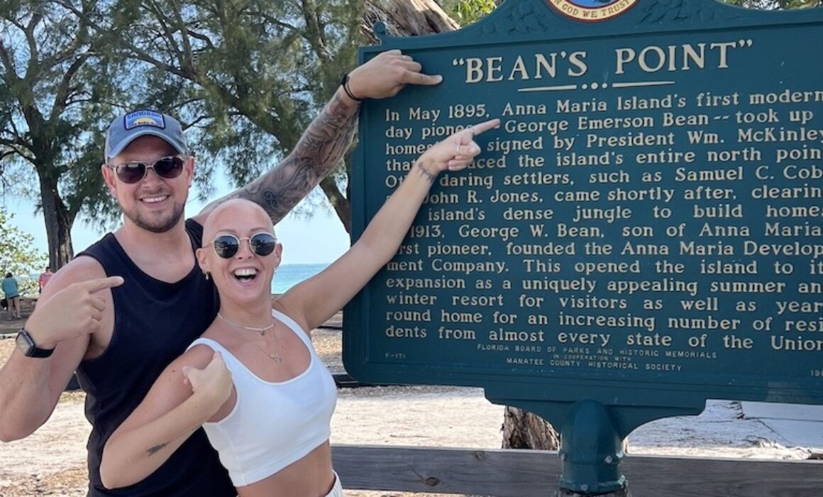 Alex and Nicky Newman at a sign reading Bean