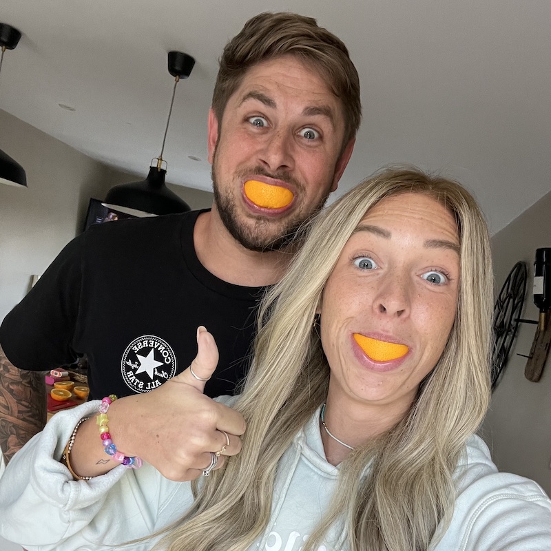 Alex and Nicky Newman posing with orange slices over their teeth